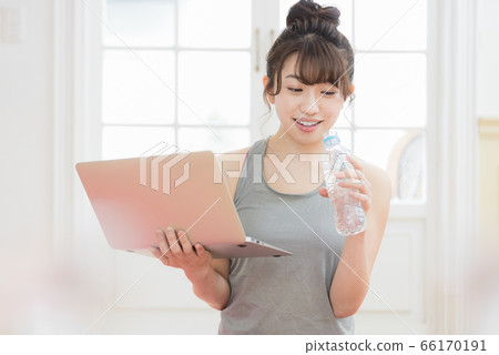 Woman looking at a laptop wearing training wear Woman looking at a laptop wearing training wear 66170191