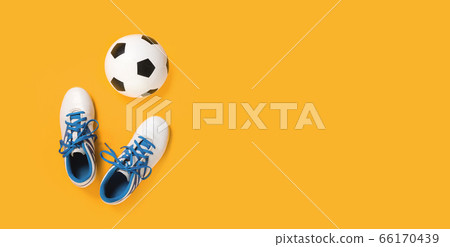 Soccer ball and cleats on yellow background 66170439