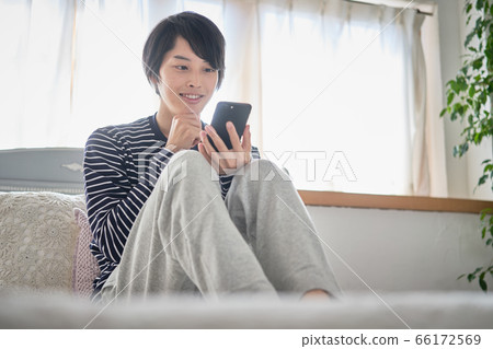 A young man looking at his smartphone at home 66172569