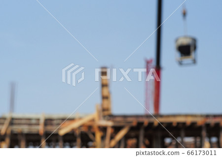 Defocused picture of crane carrying the mixed cement metal bucket at the construction site with blue sky background. Picture is blurred in purpose 66173011