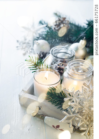 Burning candle and Christmas decoration over snow and wooden background, elegant low-key shot with festive mood 66175728