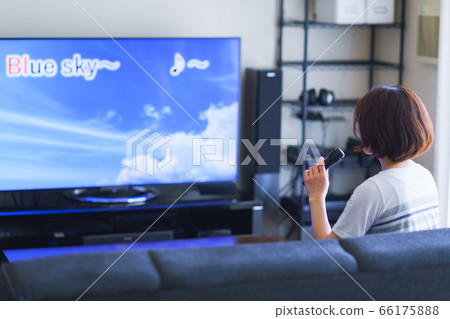 A woman enjoying "home karaoke" with a home game console app A woman enjoying "home karaoke" with a home game console app 66175888