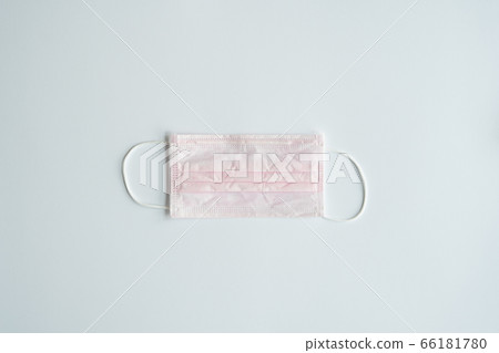 Used pink medical mask on a gray background. Disposable 3-ply medical mask to cover the mouth and nose to prevent coronavirus. Coronavirus quarantine. Antivirus medical mask for protection covid-19. 66181780