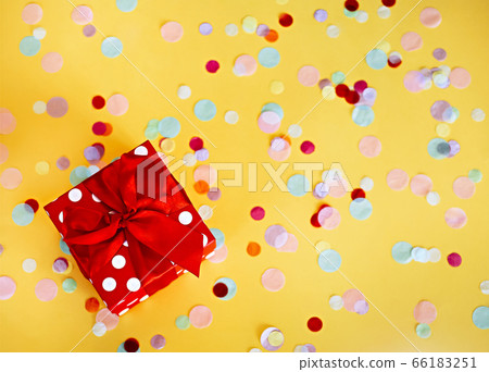 Red gift box and colorful confetti on yellow 66183251