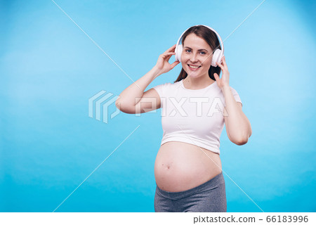 Young cheerful pregnant female with toothy smile and enjoying her favorite music 66183996