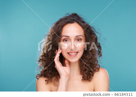 Gorgeous young woman with toothy smile and curly hair having undereye mask Gorgeous young woman with toothy smile and curly hair having undereye mask 66184311
