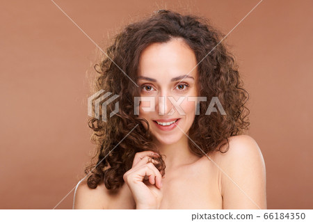 Beautiful female with bare shoulders and wavy hair standing in front of camera Beautiful female with bare shoulders and wavy hair standing in front of camera 66184350