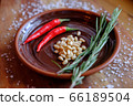 Fresh rosemary, hot red pepper and pine nuts on a clay plate on a wooden background with crystals of coarse white salt. The concept of a delicious and healthy diet. 66189504