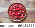 Pink peppercorns and red hot chili peppers in a clay plate standing on a wooden background. 66189825