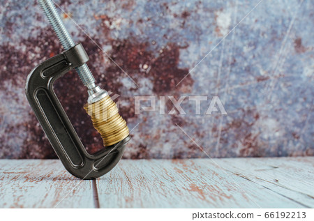 stacking coin squeezing in a G-clamp as a financial crisis concept 66192213