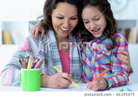 Little cute girl with mother drawing at the table at home 66195075