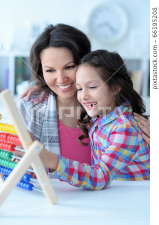 Mother teaching her daughter to use abacus indoors 66195208