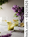 Fresh summer lemonnad with mint and kiwi stands on the table. Nearby is a bouquet of lilacs in a purple vase. 66203626
