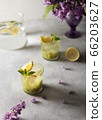 Fresh summer lemonnad with mint and kiwi stands on the table. Nearby is a bouquet of lilacs in a purple vase. 66203627