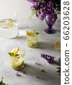 Fresh summer lemonnad with mint and kiwi stands on the table. Nearby is a bouquet of lilacs in a purple vase. 66203628