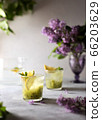Fresh summer lemonnad with mint and kiwi stands on the table. Nearby is a bouquet of lilacs in a purple vase. 66203629