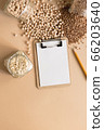 Cereals in glass jars on the table next to a Notepad and pencil. Space for text, white sheet of paper. 66203640