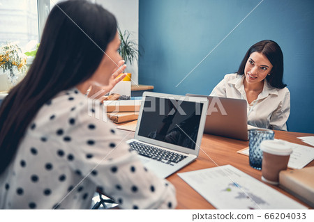 Pretty ladies sitting in office while talking 66204033