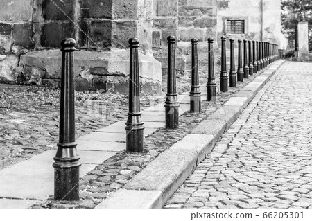 Row of iron pillars between cobbled street and pedestrian sidewalks Row of iron pillars between cobbled street and pedestrian sidewalks 66205301