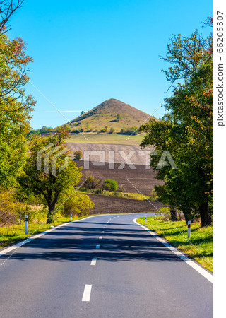 Asphalt road and typical conical volcanic hill of Central Bohemian Highlands on sunny summer day, Czech Republic Asphalt road and typical conical volcanic hill of Central Bohemian Highlands on sunny summer day, Czech Republic 66205307