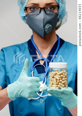 medical doctor nurse woman wearing protective mask and rubber or latex gloves - holding pills medical doctor nurse woman wearing protective mask and rubber or latex gloves - holding pills 66214655