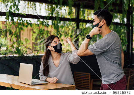 Asian woman and man friends wearing face mask outdoors. Friends greeting and shaking with elbows as new normal. Corona Virus - Covid 19 elbow bumps greeting style to prevent contact and virus spread 66216872