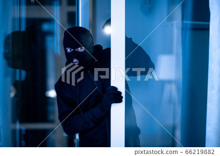 Thief breaking into apartment to steal, using torch Thief breaking into apartment to steal, using torch 66219882
