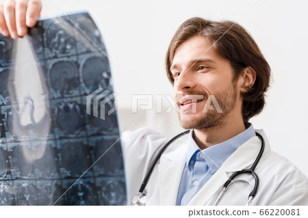 Positive doctor looking at x-ray scans of patient head 66220081