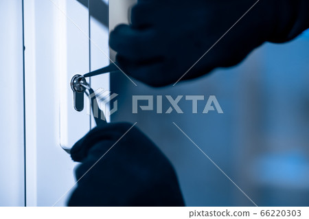 Robber in black balaclava cracking door with metal picklock 66220303