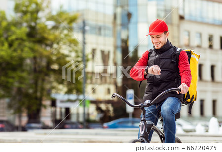 Courier On Bike Checking Time Delivering Food In City Courier On Bike Checking Time Delivering Food In City 66220475