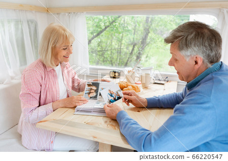 Senior married couple looking through family album with photos inside of camping vehicle Senior married couple looking through family album with photos inside of camping vehicle 66220547
