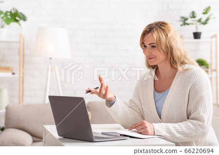 School, college and university online. Smiling female teacher holds lessons on laptop School, college and university online. Smiling female teacher holds lessons on laptop 66220694