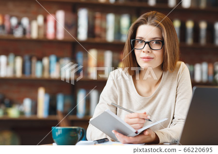 Dreamy young journalist creating article writing ideas in notebook 66220695
