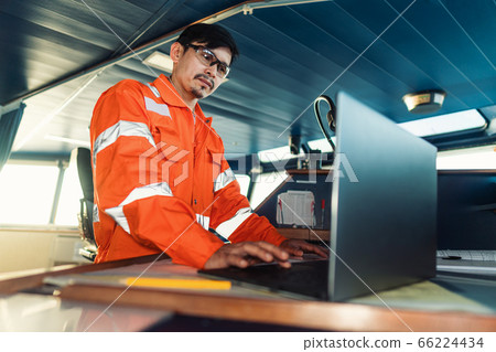 Filipino deck Officer on bridge of vessel or ship. He is using laptop, electronic paperwork at sea Filipino deck Officer on bridge of vessel or ship. He is using laptop, electronic paperwork at sea 66224434