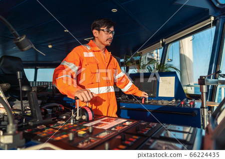 Filipino deck Officer on bridge of vessel or ship. He is speaking on GMDSS VHF radio 66224435