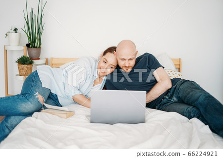 Adult married couple in casual clothing using open laptop Adult married couple in casual clothing using open laptop 66224921