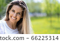 Portrait of young beautiful smiling woman on green grass in the summer outdoors 66225314