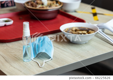 Face mask and sanitizer on table next to meal, new normal post coronavirus pandemic. 66225626