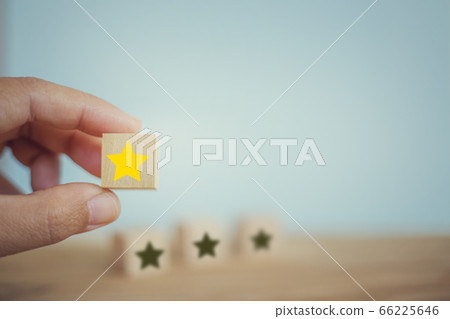 Business success: Hand chooses wooden yellow star shape on table. The best excellent business services rating customer experience concept. Business success: Hand chooses wooden yellow star shape on table. The best excellent business services rating customer experience concept. 66225646