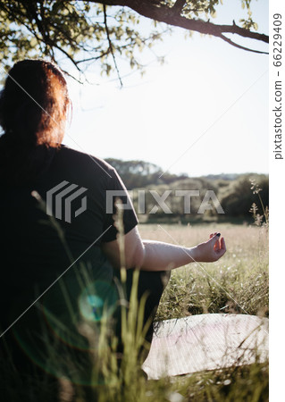 Overweight woman practicing yoga outdoors 66229409