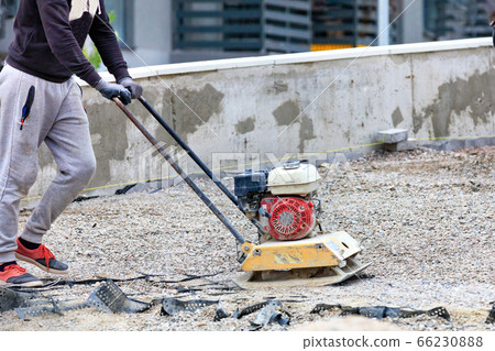 The builder compacts crushed stone with a gasoline The builder compacts crushed stone with a gasoline 66230888