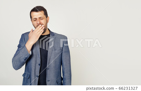 Business man on an isolated background bored yawns tired hand covering his mouth 66231327