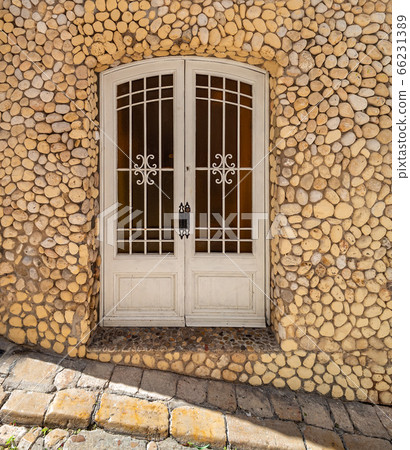 Entrance door to an old stone house decorated with pebbles. Mediterranean architecture and streets. Entrance door to an old stone house decorated with pebbles. Mediterranean architecture and streets. 66231389