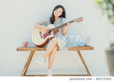 A beautiful woman playing guitar 66235920