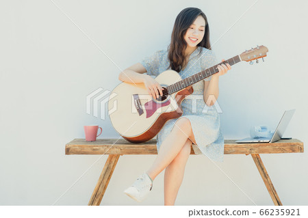 A beautiful woman playing guitar 66235921