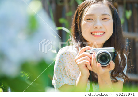 Beautiful woman holding a camera in the garden 66235971