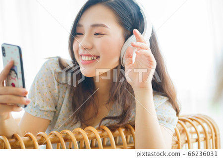 Beautiful woman wearing headphone and using smartphone at home 66236031
