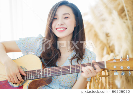 Beautiful woman playing guitar at home Beautiful woman playing guitar at home 66236050