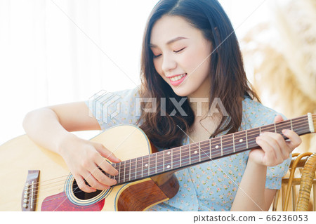 Beautiful woman playing guitar at home 66236053