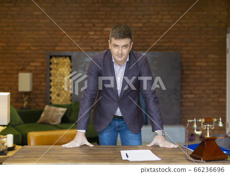 Portrait of a middle-aged businessman leaning on his desk 66236696